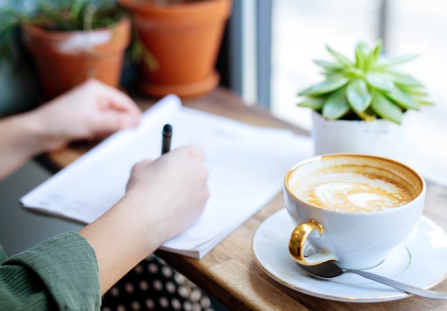 コーヒーを横に書類を書く様子